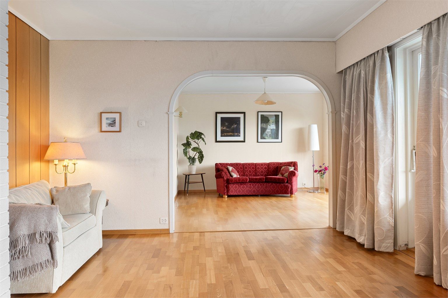 Gjennom bueåpningen ser man inn til den mer tilbaketrukne delen av stuen.