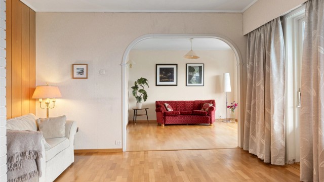 Gjennom bueåpningen ser man inn til den mer tilbaketrukne delen av stuen.