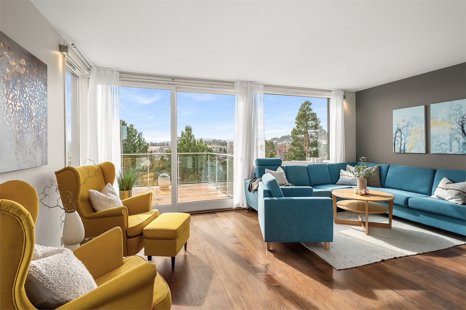 Stuen fremstår som lys, lun og innbydende, med store vindusflater og utgang til veranda som forlenger oppholdsarealet på fine dager.