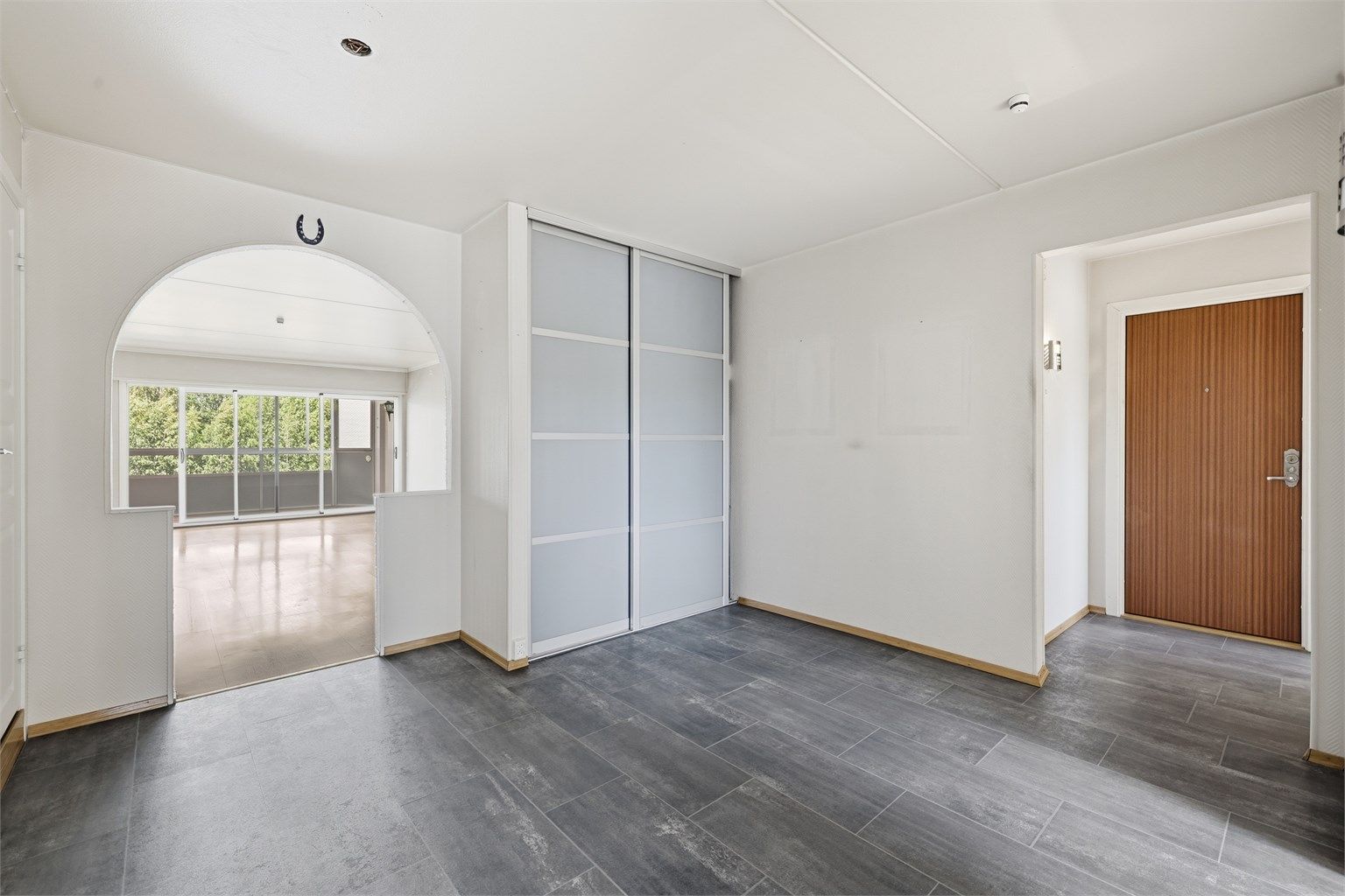 Romslig entré og gang med god plass til oppbevaring i skyvedørsgarderobe.