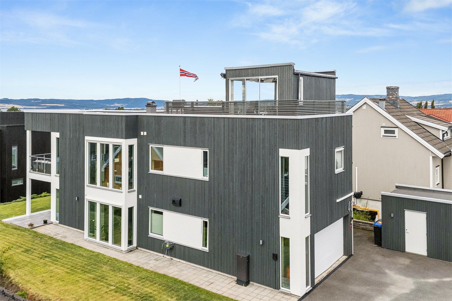 Fasade mot sør. Asfaltert gårdsplass og heller rundt boligen hvor man kan gå tørrskodd til flott terrasse på hagesiden. 