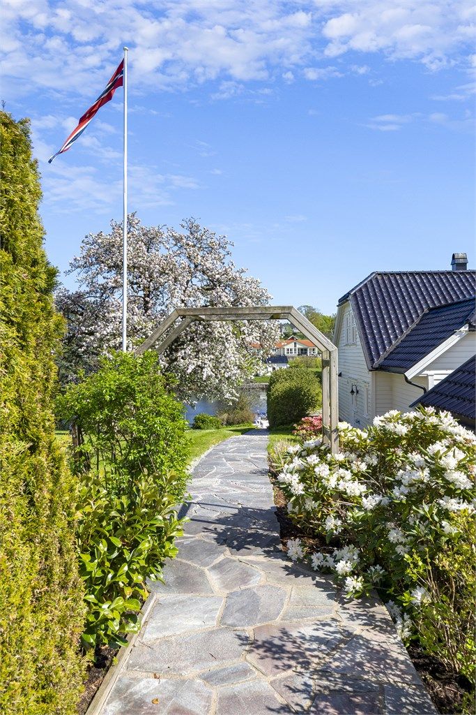 En sti belagt med skifer leder ned gjennom hagen mot elven og bryggeanlegget.