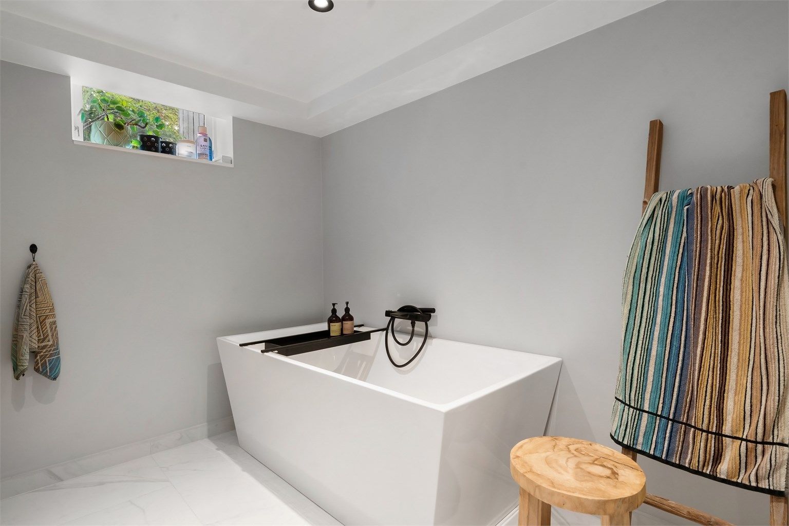 Badet har servantinnredning, vegghengt toalett og frittstående badekar. Det er malt himling med downlights