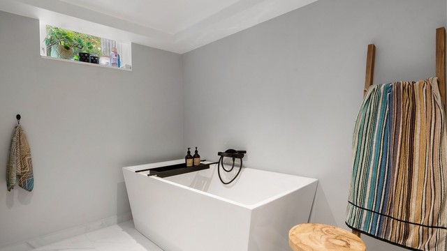 Badet har servantinnredning, vegghengt toalett og frittstående badekar. Det er malt himling med downlights