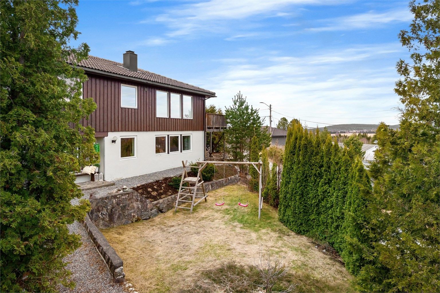 Tomten er pent opparbeidet med plenarealer og forstøtningsmurer i naturstein, et trygt sted for barn å leke.