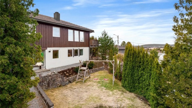 Tomten er pent opparbeidet med plenarealer og forstøtningsmurer i naturstein, et trygt sted for barn å leke.