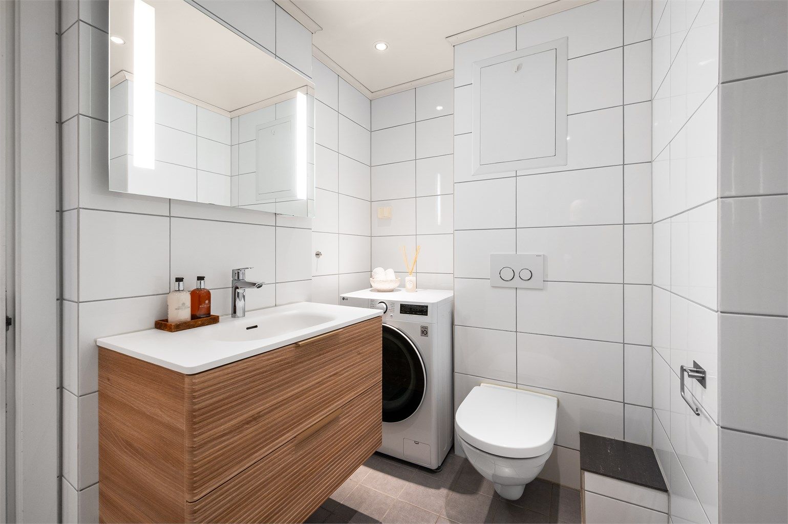 Praktisk innredet bad med vegghengt toalett og opplegg for vaskemaskin.