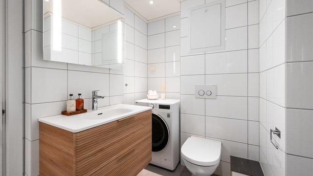 Praktisk innredet bad med vegghengt toalett og opplegg for vaskemaskin.