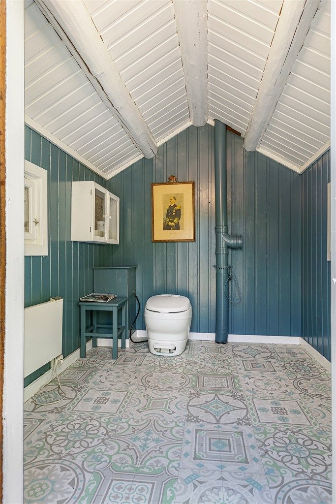 Pen utedo med tradisjonelt preg, oppusset med panelvegger i mørk blåtone og flismønstret gulvbelegg.