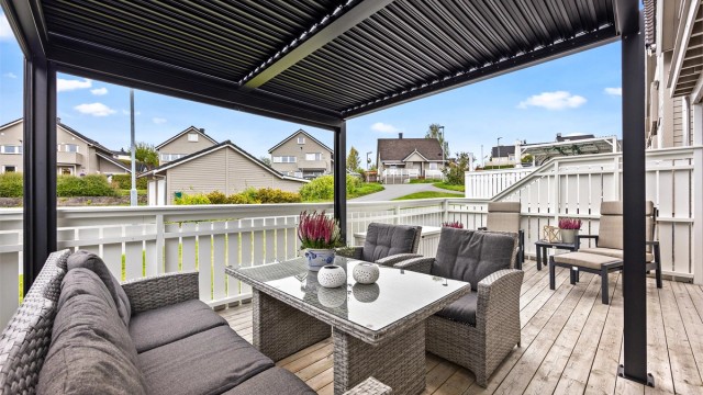 Vestvendt terrasse med pergola og god plass til utemøbler.