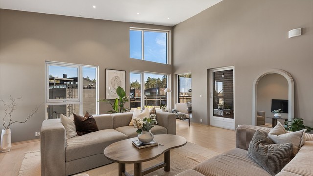 Stuen har en imponerende takhøyde og store vindusflater som gir en luftig atmosfære. Her er det gulvvarme og utgang til en balkong på 20 m².