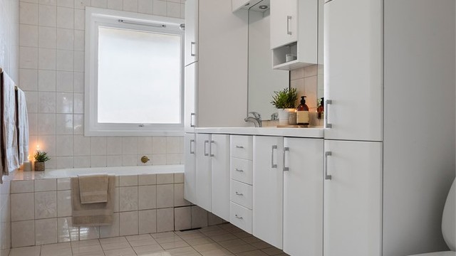Badet er utstyrt med badekar, dobbel servant, rikelig med skapplass og gulvmontert toalett.