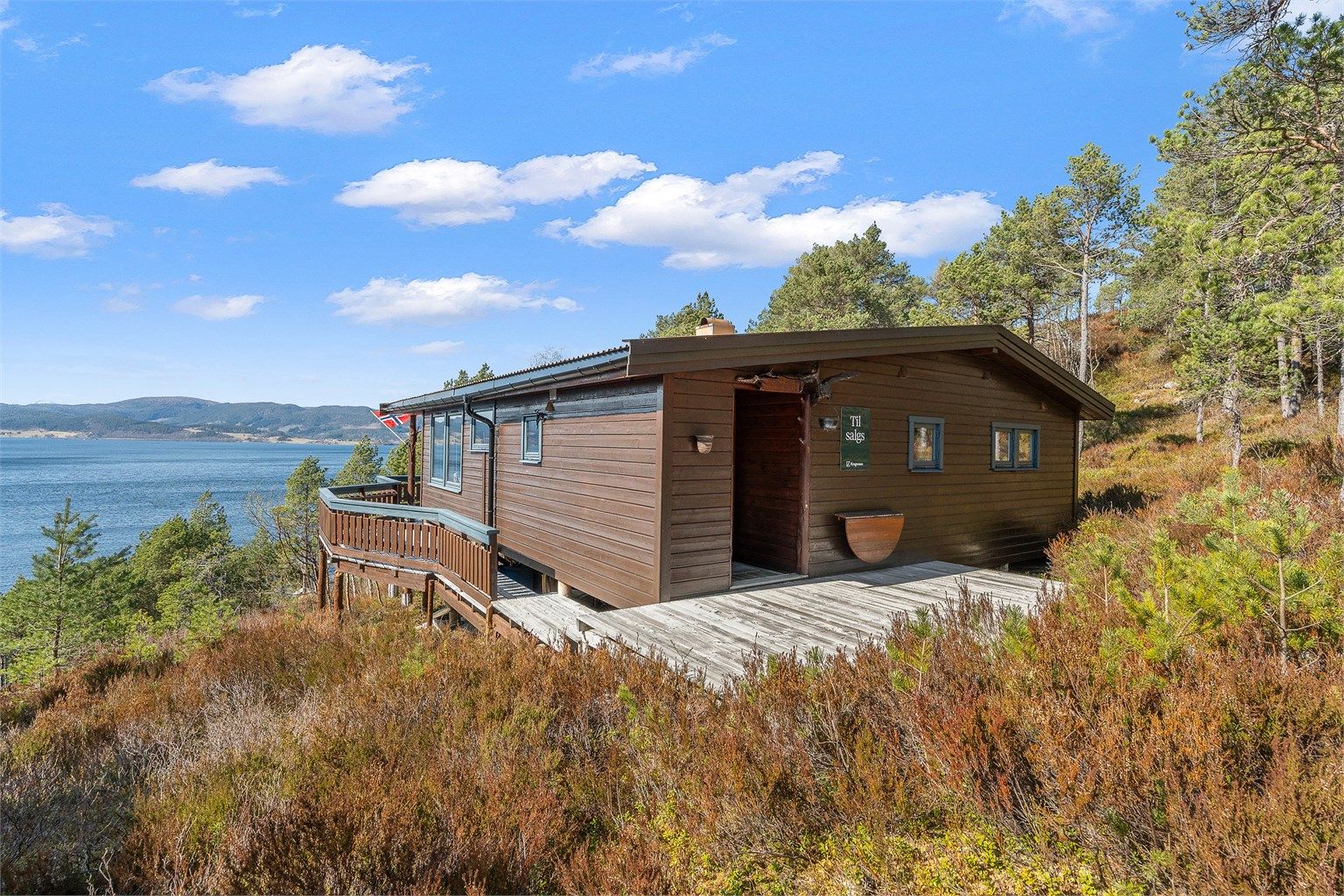 Hytta ligger flott til i terrenget med terrasse og utsikt mot fjorden – en perfekt ramme for fritidslivet.