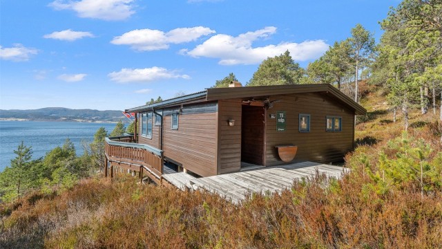 Hytta ligger flott til i terrenget med terrasse og utsikt mot fjorden – en perfekt ramme for fritidslivet.