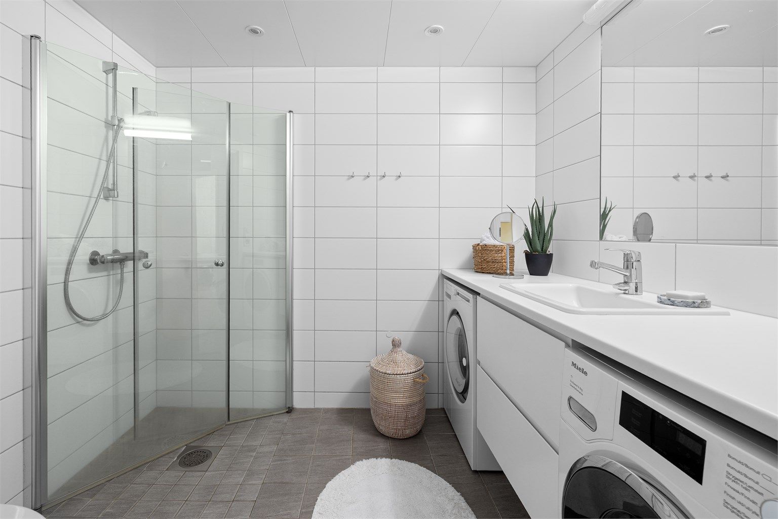 Baderom fra 2019 med opplegg for vaskemaskin, samt mulighet for tørketrommel. Videre er det flislagte gulv med gulvvarme, flislagte vegger og malte himlingsflater med downlights. 