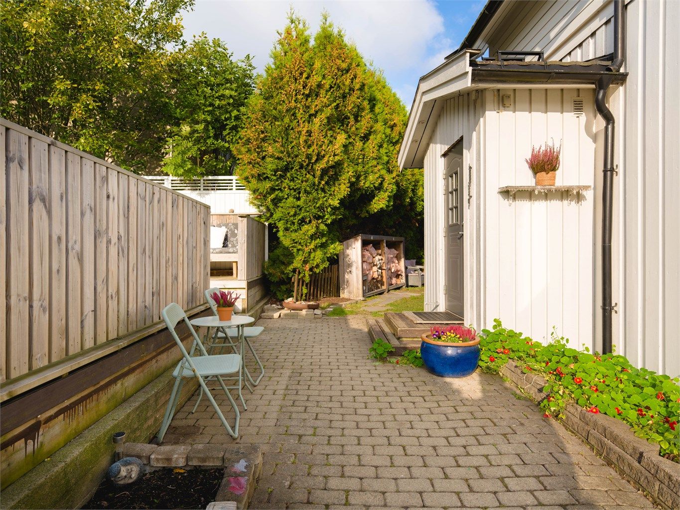 Steinlagt adkomst fra garasjen til boligen og et hyggelig, skjermet uteområde.