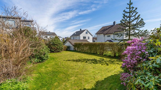 En veletablert hage som rammer inn eiendommen og skaper en privat atmosfære.