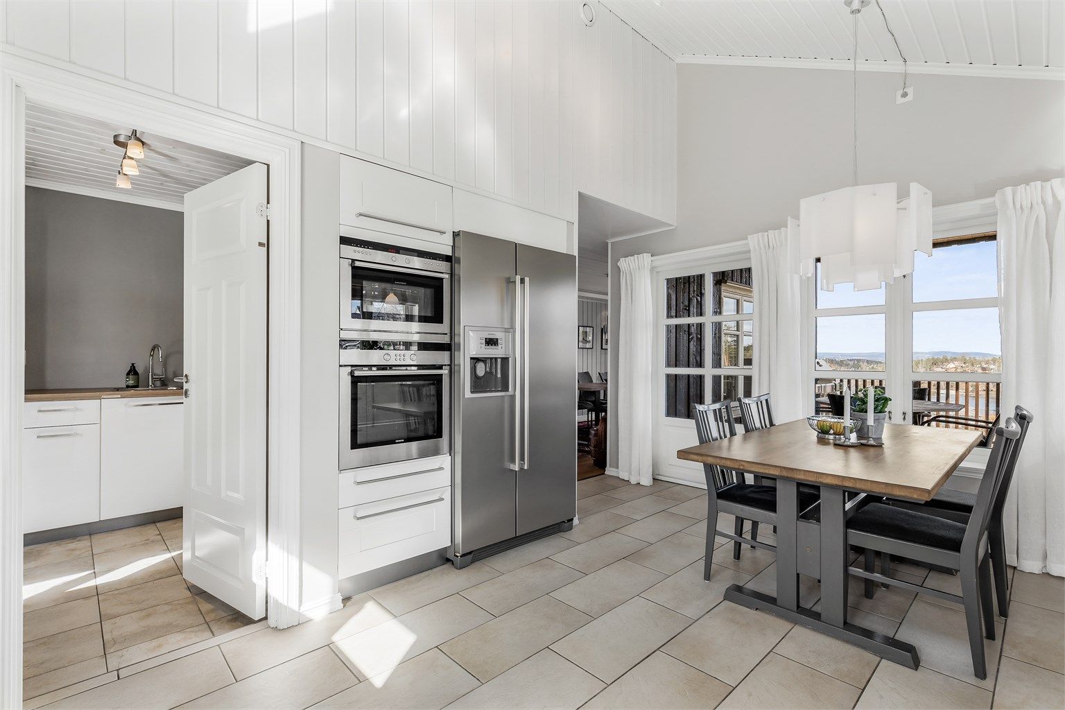 Åpen kjøkkenløsning. Innredning fra byggeår. Profilerte fronter. Benkeplate av tre og stein.  Nedfelt kjøkkenvask med armatur. Stikkontakter over kjøkkenbenk. Frittstående kjøleskap med fryser.