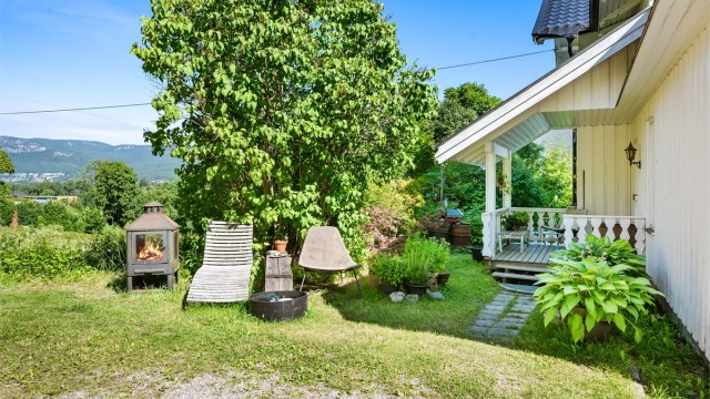 Tomten er opparbeidet med gruset gårdsplass, plenarealer og diverse beplantninger.