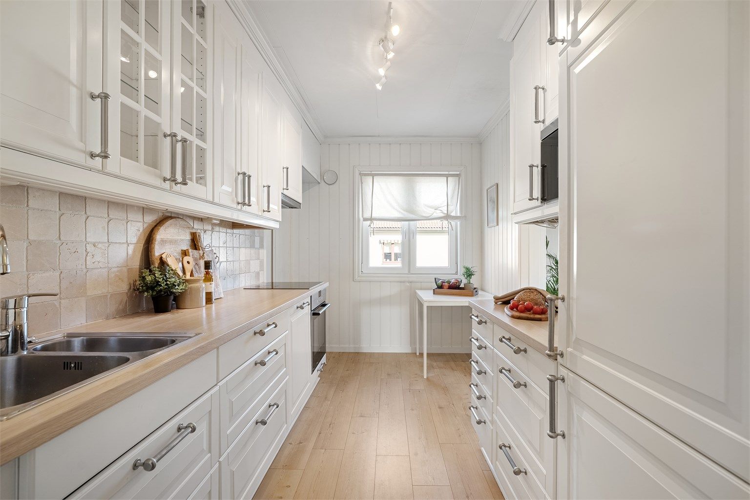 Stilrent kjøkken med lyse fronter og god benkeplass.