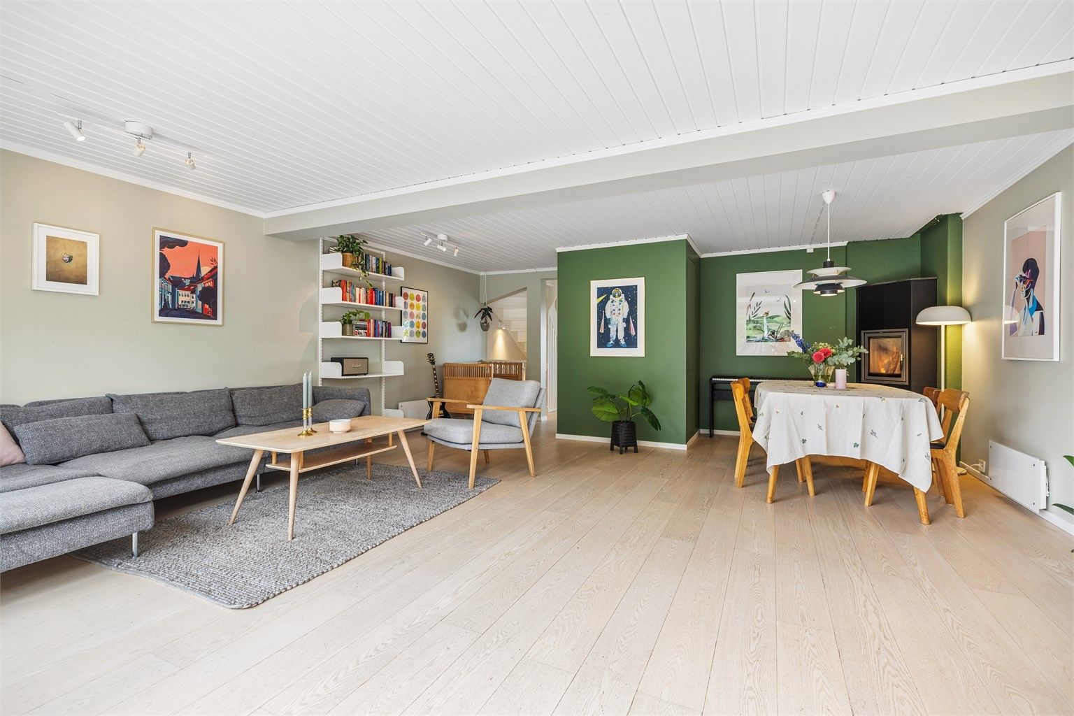 Romslig stue med god plass til både sofagruppe og spisebord. Den moderne peisovnen gir god varme i boligen. 