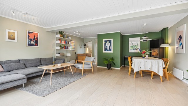 Romslig stue med god plass til både sofagruppe og spisebord. Den moderne peisovnen gir god varme i boligen.