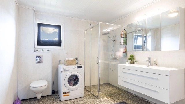 Bad i 2. etasje fra 20121/2022. Gulv med belegg. Vegger med våtromsplater, og himling med mdf panel. Innredning med slette fronter. Heldekkende servant og speilskap. Opplegg for vaskemaskin. Vegghengt toalett. Dusjhjørne med glassvegg.