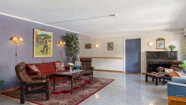 Sameiets felles oppholdsstue med sittegruppe og piano.
