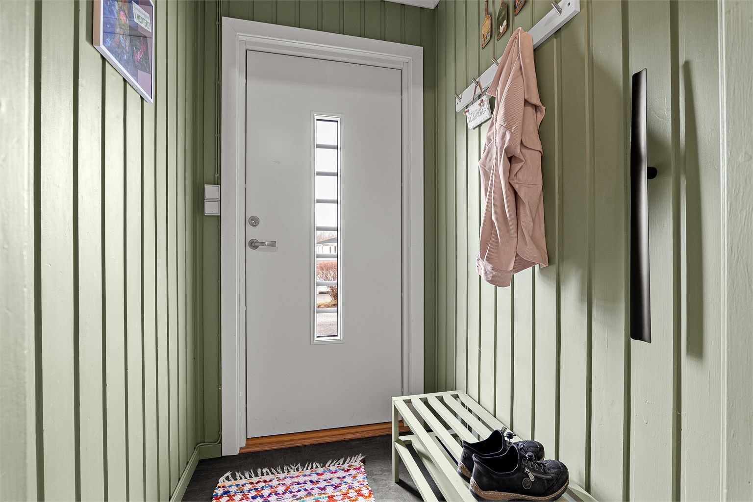 Velkommen inn i en lys entré med plass til oppbevaring av yttertøy