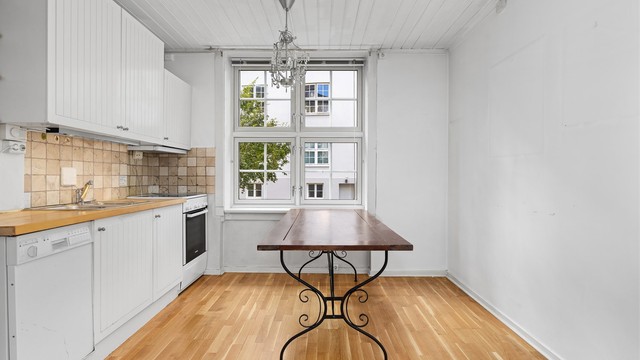 Kjøkkenet her holdt i lyse fargevalg og det store vinduet slipper inn mye lys i rommet. Her er det også god plass til å ha et stort spisebord eller annen valgt møblering