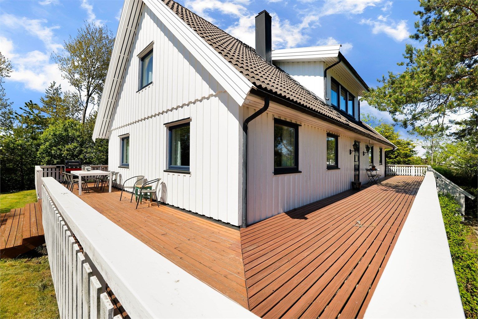 En omfangsrik terrasse på nesten 100 kvm. omfavner boligen og gir anledning til å følge solens gang.