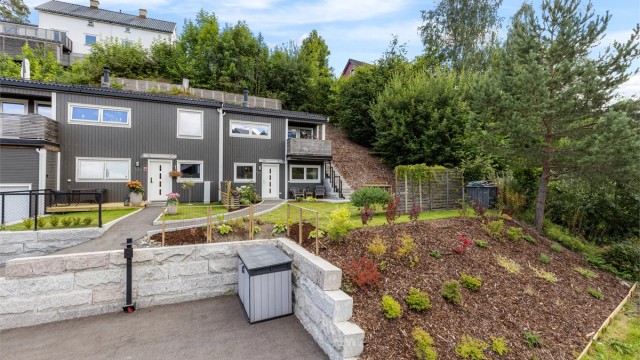 Boligens inngangsparti er pent opparbeidet med plen, belegningsstein og diverse beplantninger. På den sørvestlige siden av bygningen er det en trapp som leder opp til takterrassen.