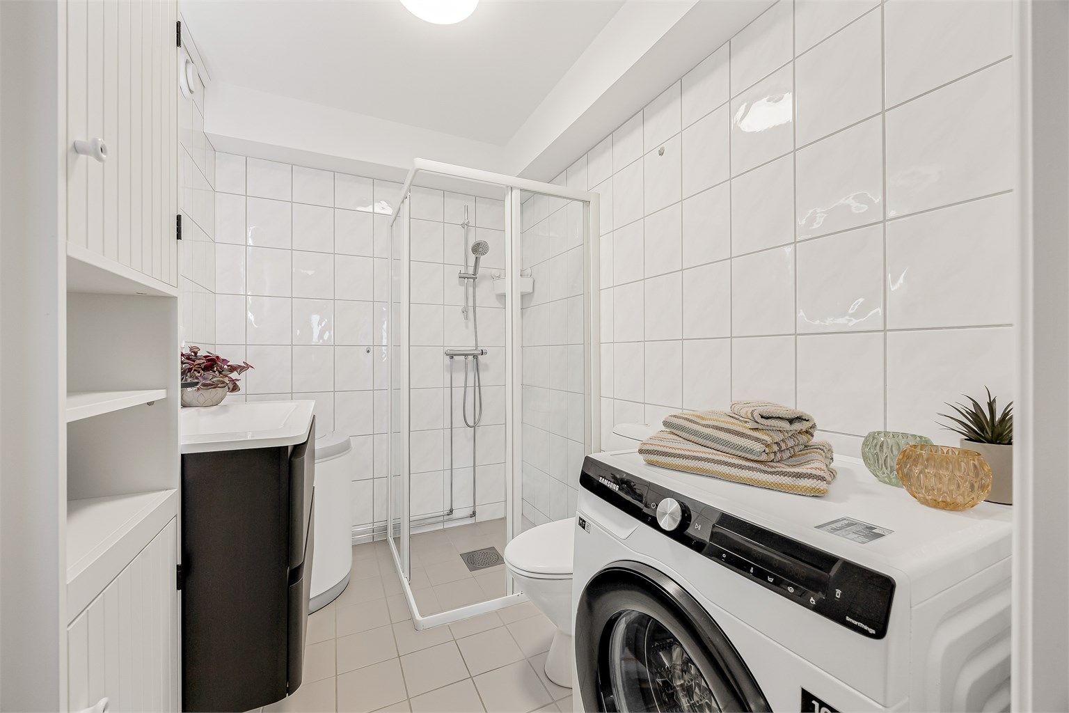 Badet har opplegg for vaskemaskin og et dusjhjørne med innfellbare dører.