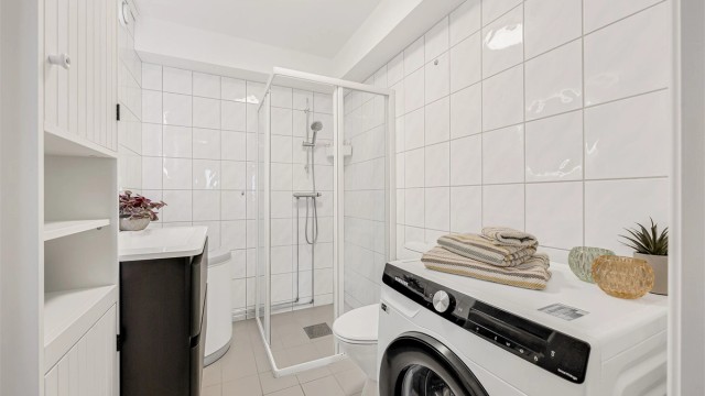 Badet har opplegg for vaskemaskin og et dusjhjørne med innfellbare dører.