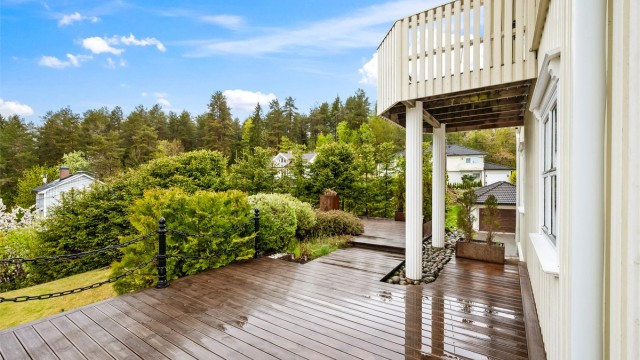 Den store terrassen strekker seg rundt deler av huset og har flere soner for utemøbler.