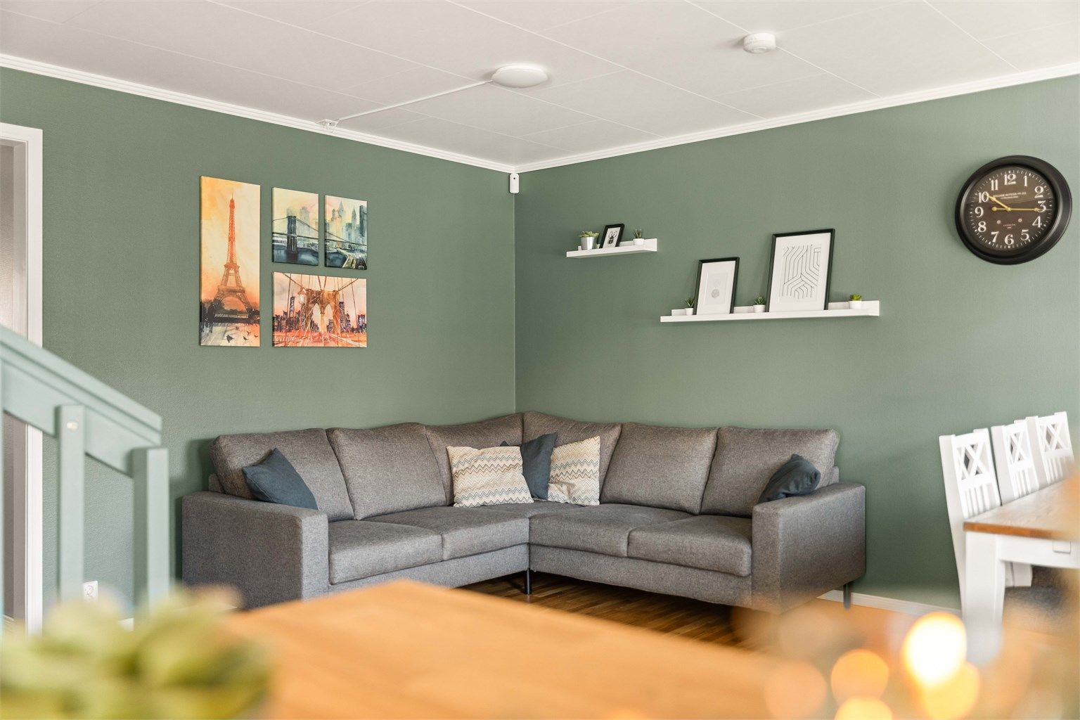 Lys og sosial stue i åpen løsning. De lune, grønne veggene skaper en behagelig atmosfære og en moderne ramme for dine møbler.