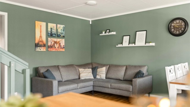 Lys og sosial stue i åpen løsning. De lune, grønne veggene skaper en behagelig atmosfære og en moderne ramme for dine møbler.