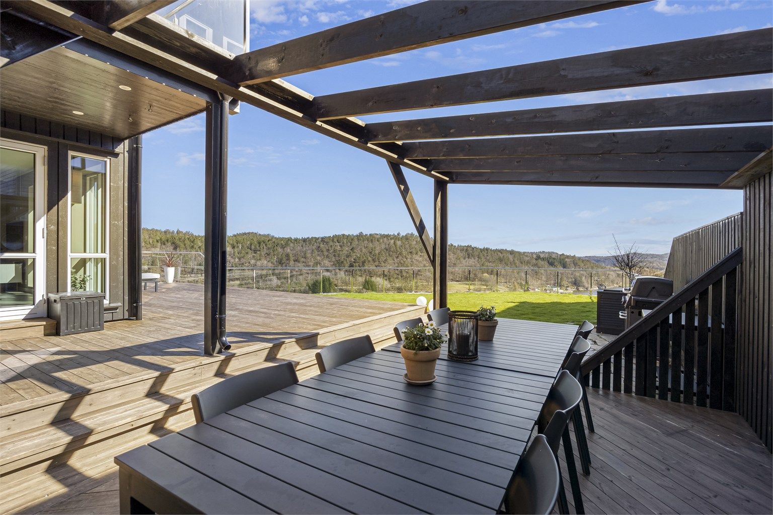 En del av terrassen har en pergola som skaper en lun og definert sone for utendørs spiseplass.