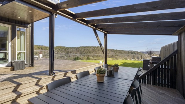 En del av terrassen har en pergola som skaper en lun og definert sone for utendørs spiseplass.