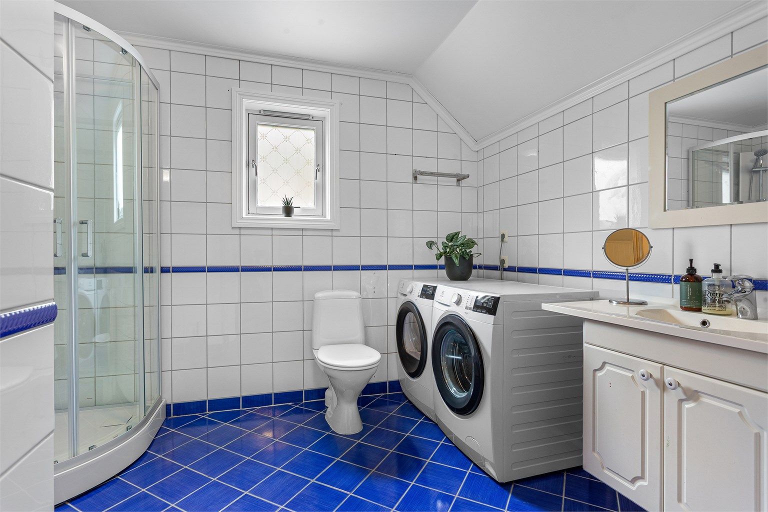 Badet er fra byggeåret og er utstyrt med gulvstående toalett, dusjkabinett samt servantinnredning.