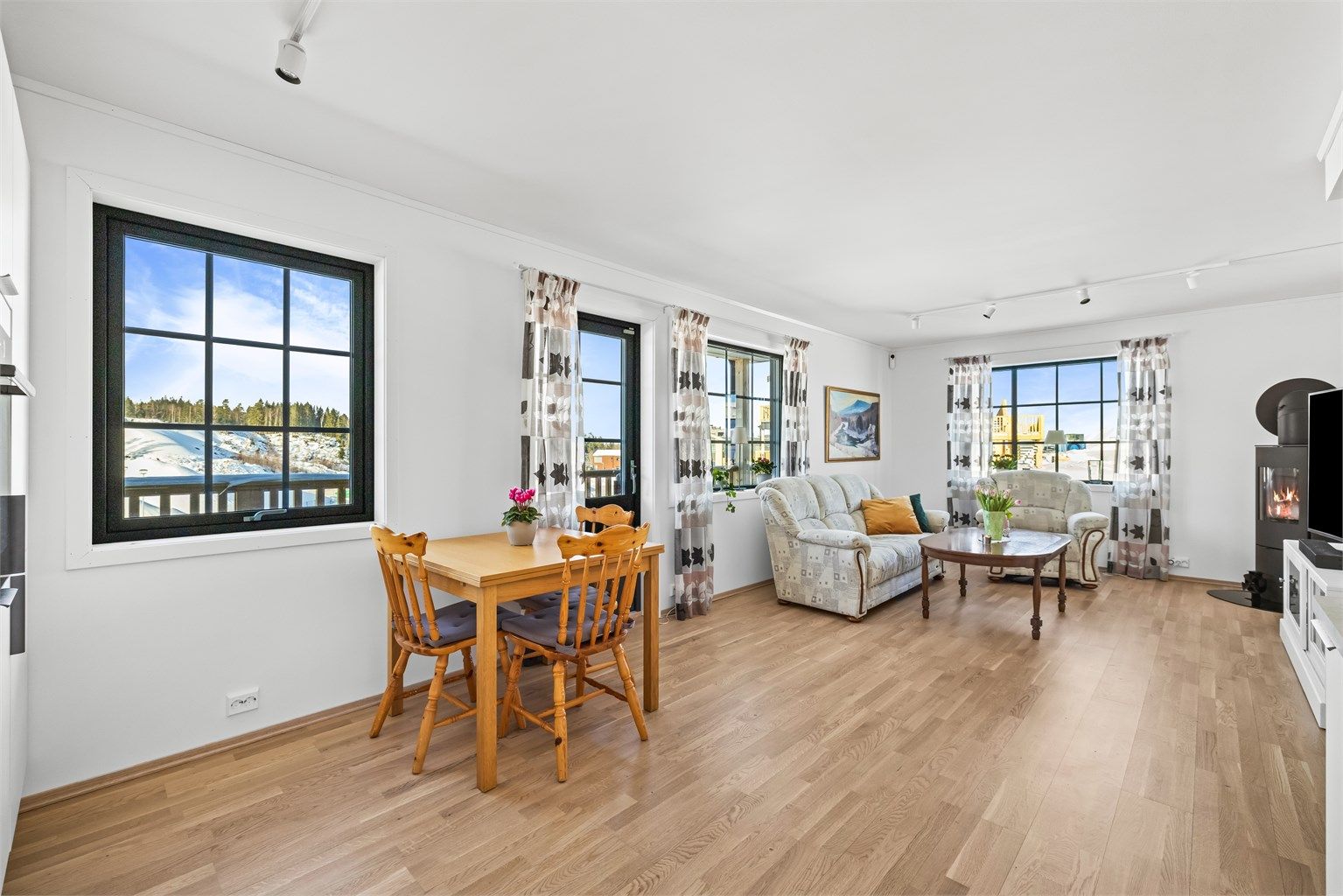 Den åpne løsningen mellom stue og kjøkken skaper en sosial og luftig atmosfære.