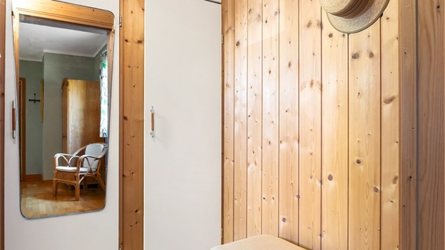 Garderobeavdeling med panelte vegger, speil og skapinnredning.