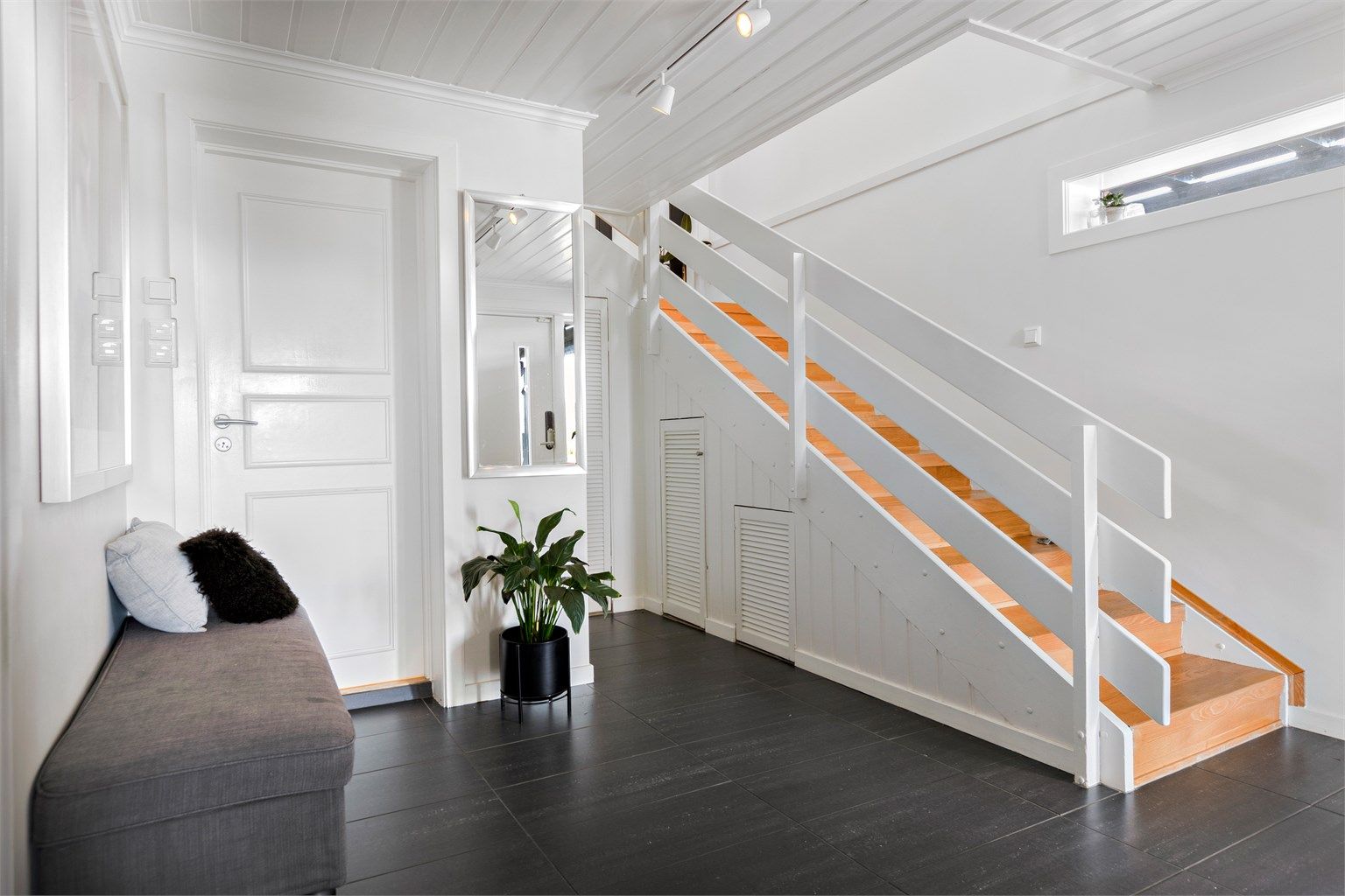 Entréen har varme i gulv og god plass. Trappen, modernisert i 1998, leder opp til hovedetasjen.