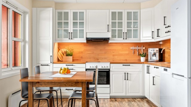 Kjøkkenet har en praktisk hjørneløsning med hvite, profilerte fronter og benkeplate i heltre.