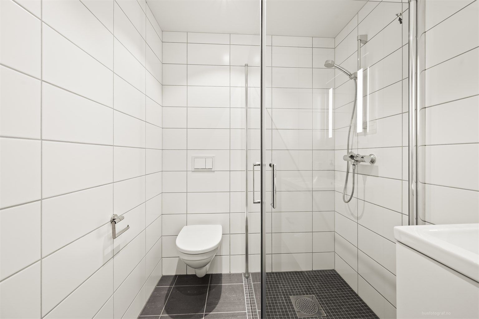 Badet har dusjhjørne med foldedører av glass.
