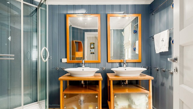 Lyst og romslig bad i 1. etasje med malte overflater og klassisk tregulv. Rommet er smakfullt innredet med to servanter med store speil, høyskap, og møblet er i solid heltre. Dusjkabinett og toalett er montert.