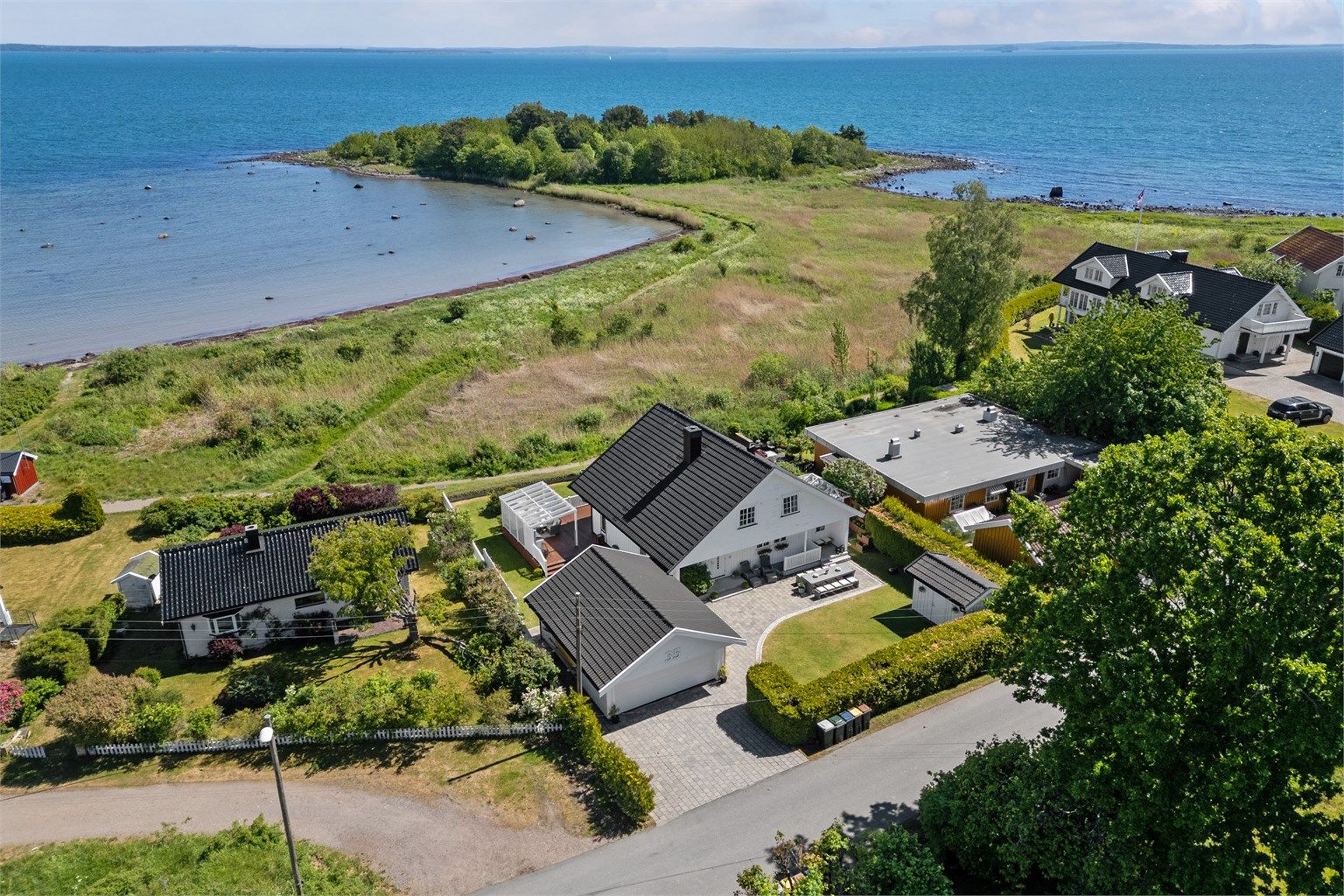 Gårdsplassen er steinsatt og strekker seg over i en markterrasse foran inngangspartiet i sydvest, hvor den er pent kantet med stein mot plenarealene. 