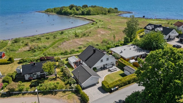 Gårdsplassen er steinsatt og strekker seg over i en markterrasse foran inngangspartiet i sydvest, hvor den er pent kantet med stein mot plenarealene.