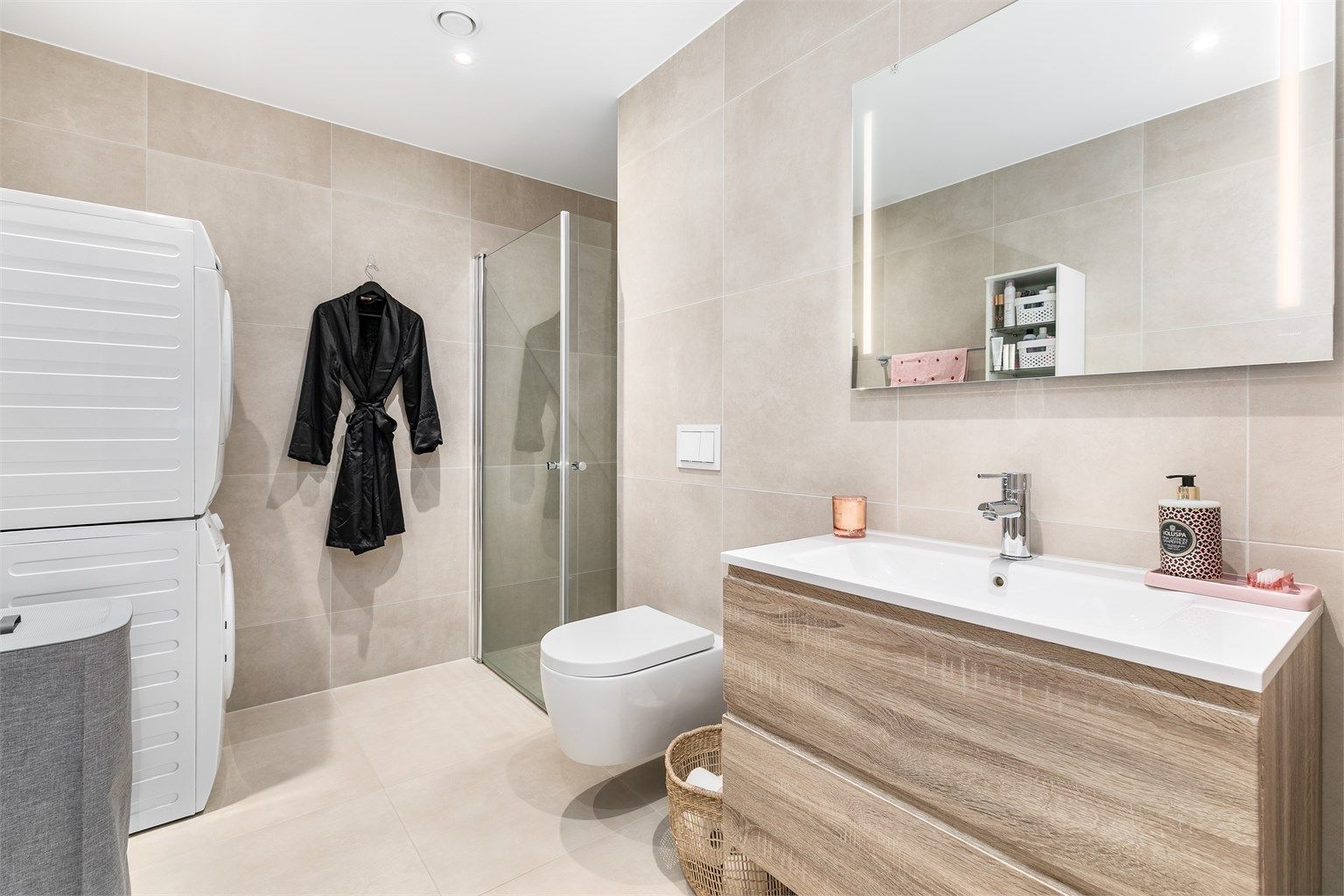 Like fliser av storformat på både veggene og gulvet utenom dusjhjørnet gir badet helhet. Himlingens innfelte spotter kan dimmes til ønsket styrke.