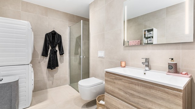 Like fliser av storformat på både veggene og gulvet utenom dusjhjørnet gir badet helhet. Himlingens innfelte spotter kan dimmes til ønsket styrke.